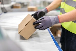 Close-up of a person’s gloved hands lifting a box-min