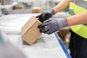Close-up of a person’s gloved hands lifting a box
